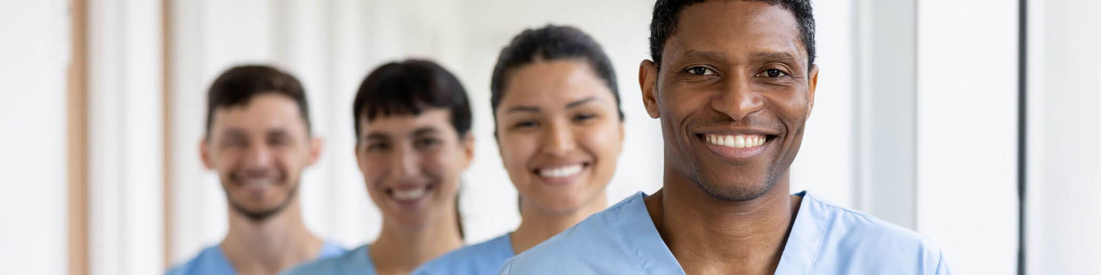 A group of men and women wearing blue scrubs and standing in a staggered line