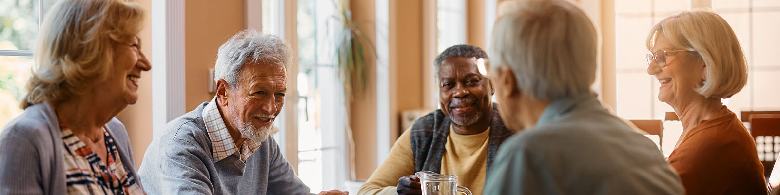 A group of senior men and women sitting together at a dining table in a senior living facility