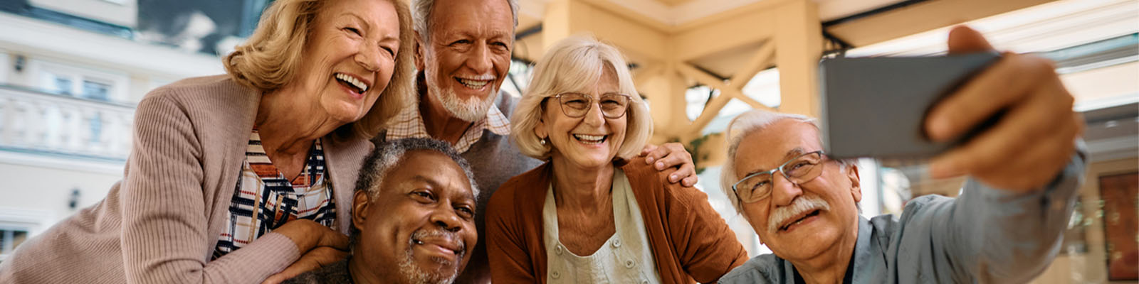 A group of senior men and women huddled together to take a selfie as they smile